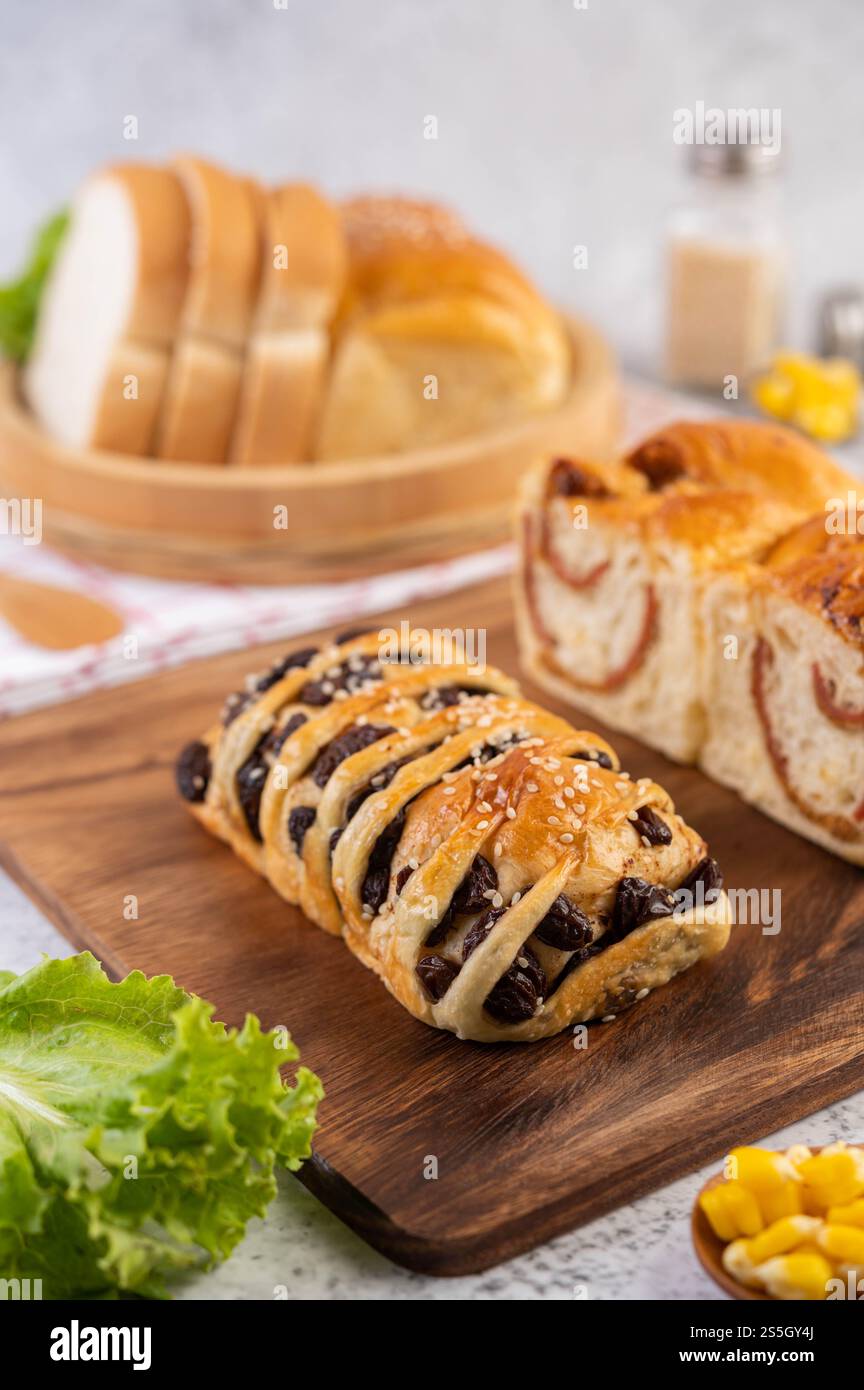 Pane in un vassoio di legno su un panno rosso e bianco con lattuga e mais. Foto Stock