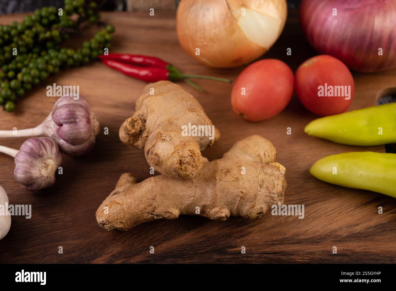 Zenzero, peperoncino, aglio e semi di pepe fresco sul pavimento in legno. Messa a fuoco selettiva. Foto Stock