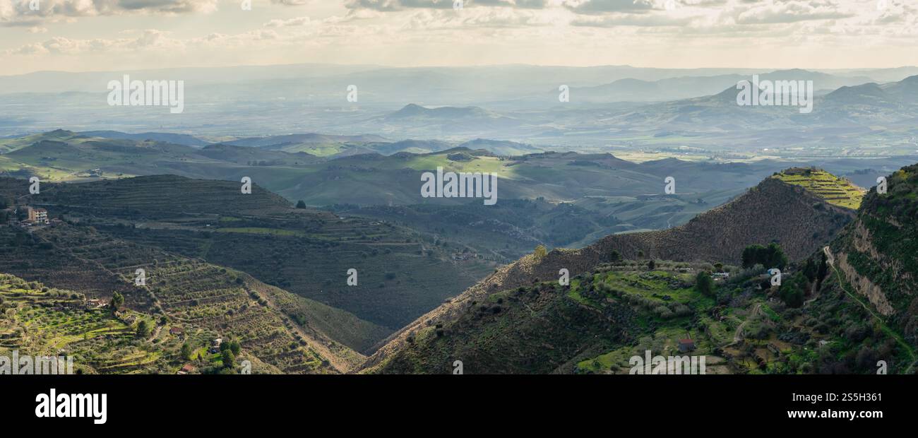 Paesaggio pittoresco della campagna siciliana: Colline ondulate, terrazze verdeggianti, fattorie rurali e oliveti sotto la luce soffusa del sole: Autentica Medite Foto Stock