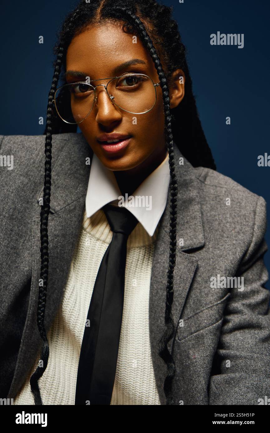 La giovane donna trasuda fiducia nel blazer e nella cravatta grigi, mostrando il suo stile e il suo fascino unici. Foto Stock