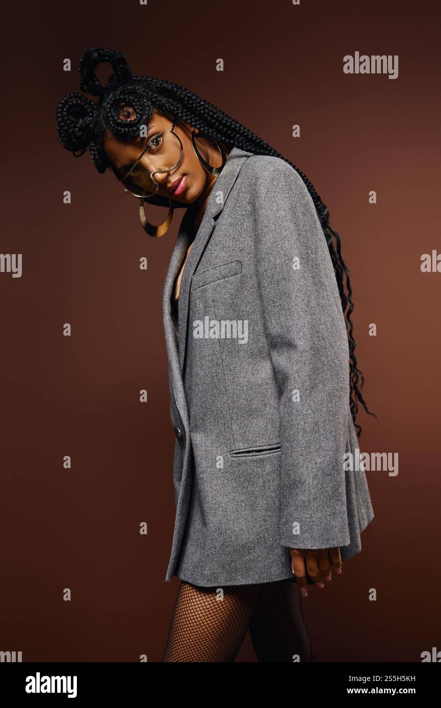 Una giovane donna trasuda fiducia in un elegante blazer grigio e in trecce eleganti. Foto Stock