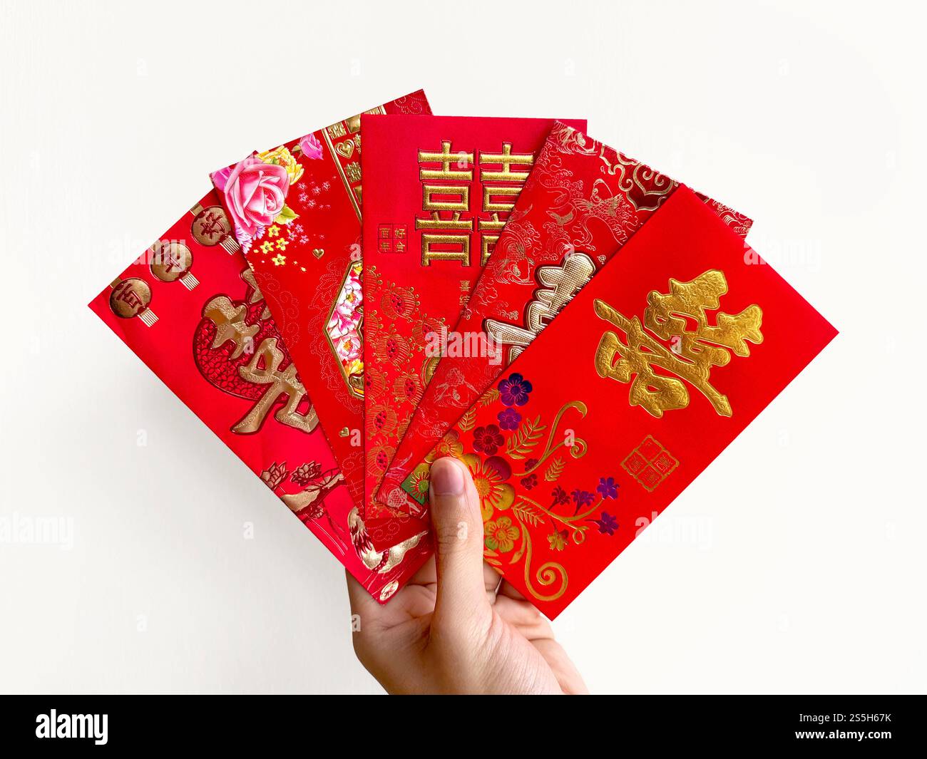 Mano che regge buste rosse cinesi, note anche come hongbao o angpao. La busta rossa è piena di soldi e famosa per il matrimonio cinese. Foto Stock