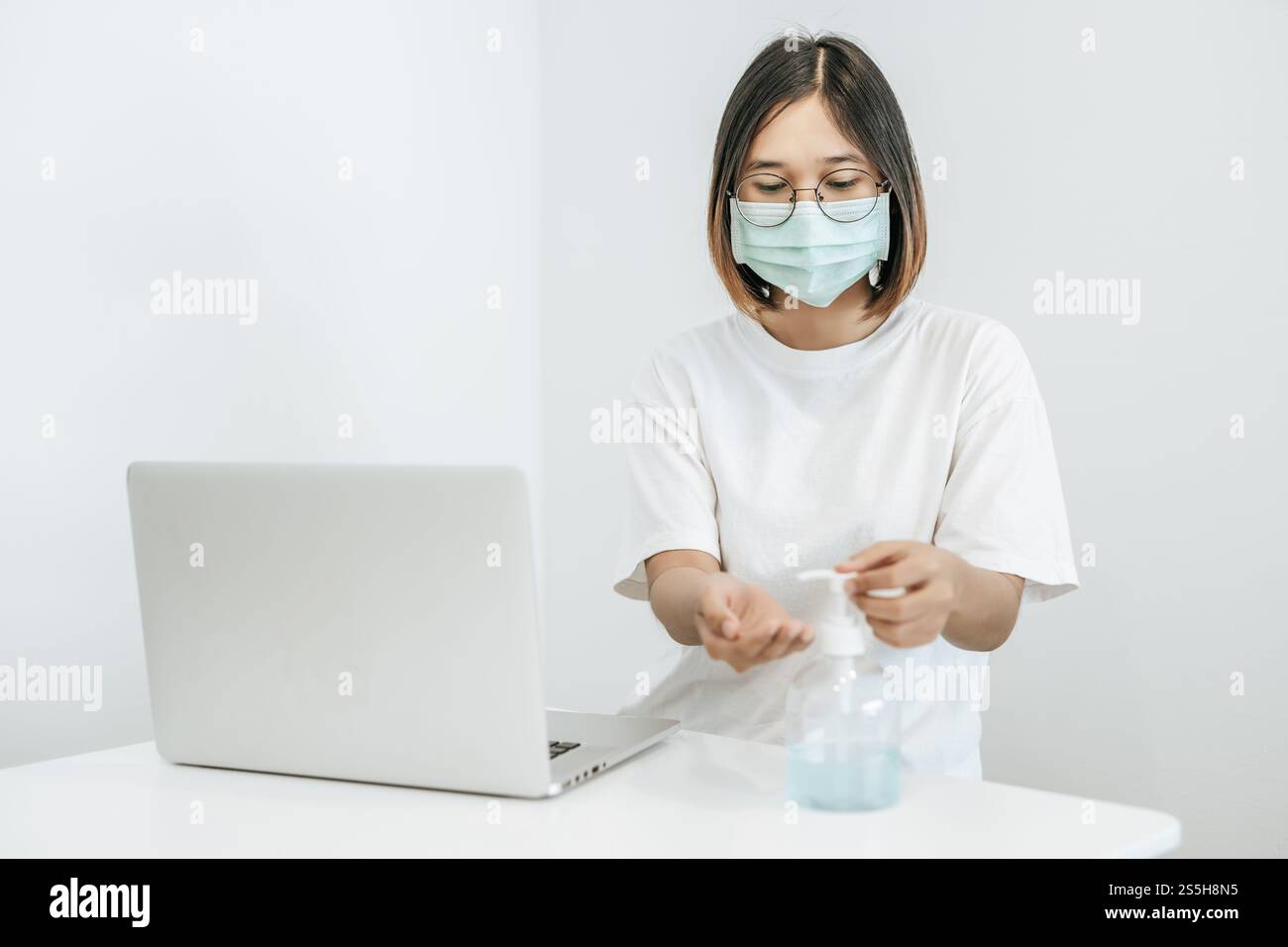 Donne che indossano camicie bianche che premono il gel per lavarsi le mani e pulire le mani. Foto Stock