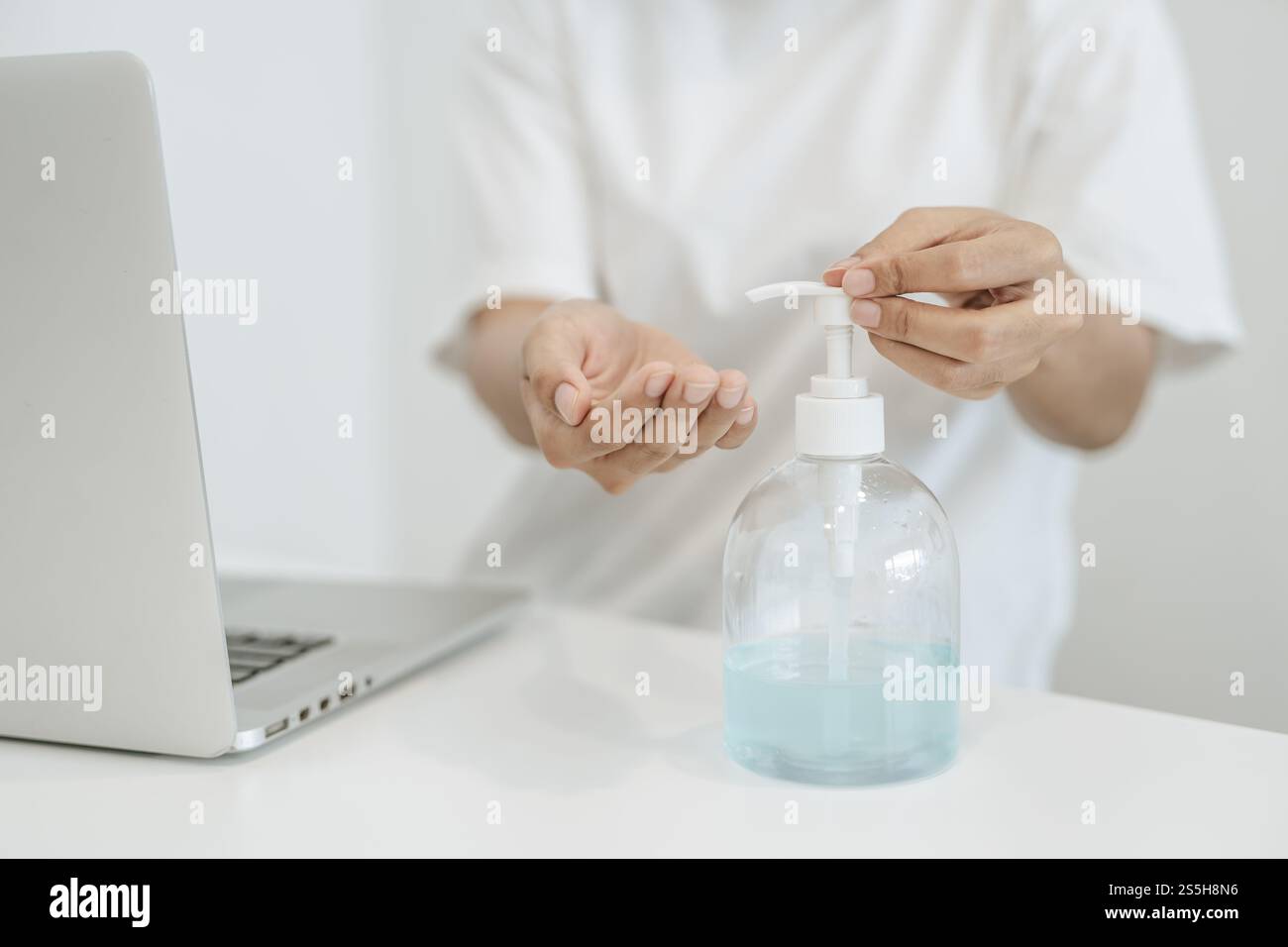 Donne che indossano camicie bianche che premono il gel per lavarsi le mani e pulire le mani. Foto Stock