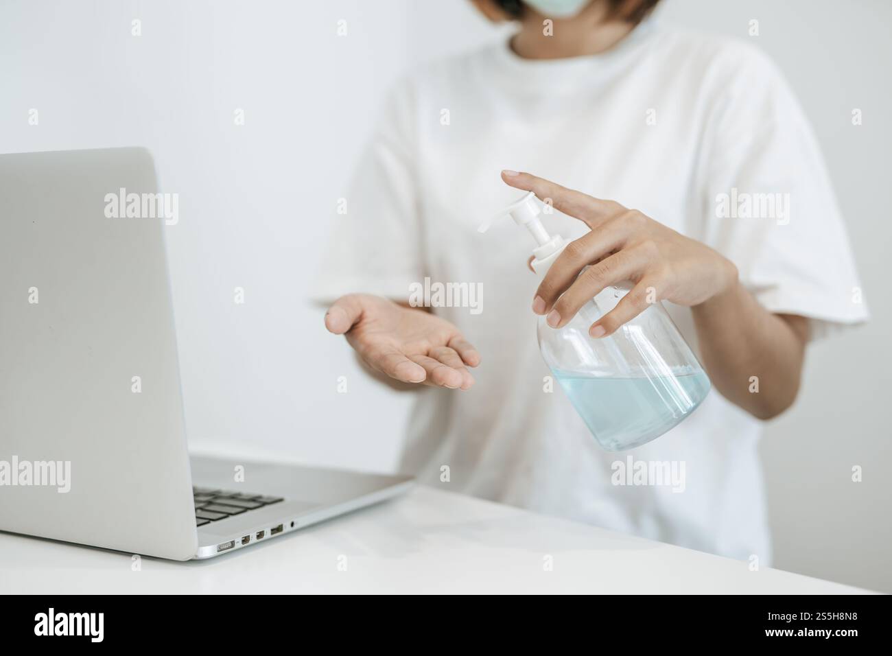 Donne che indossano camicie bianche che premono il gel per lavarsi le mani e pulire le mani. Foto Stock