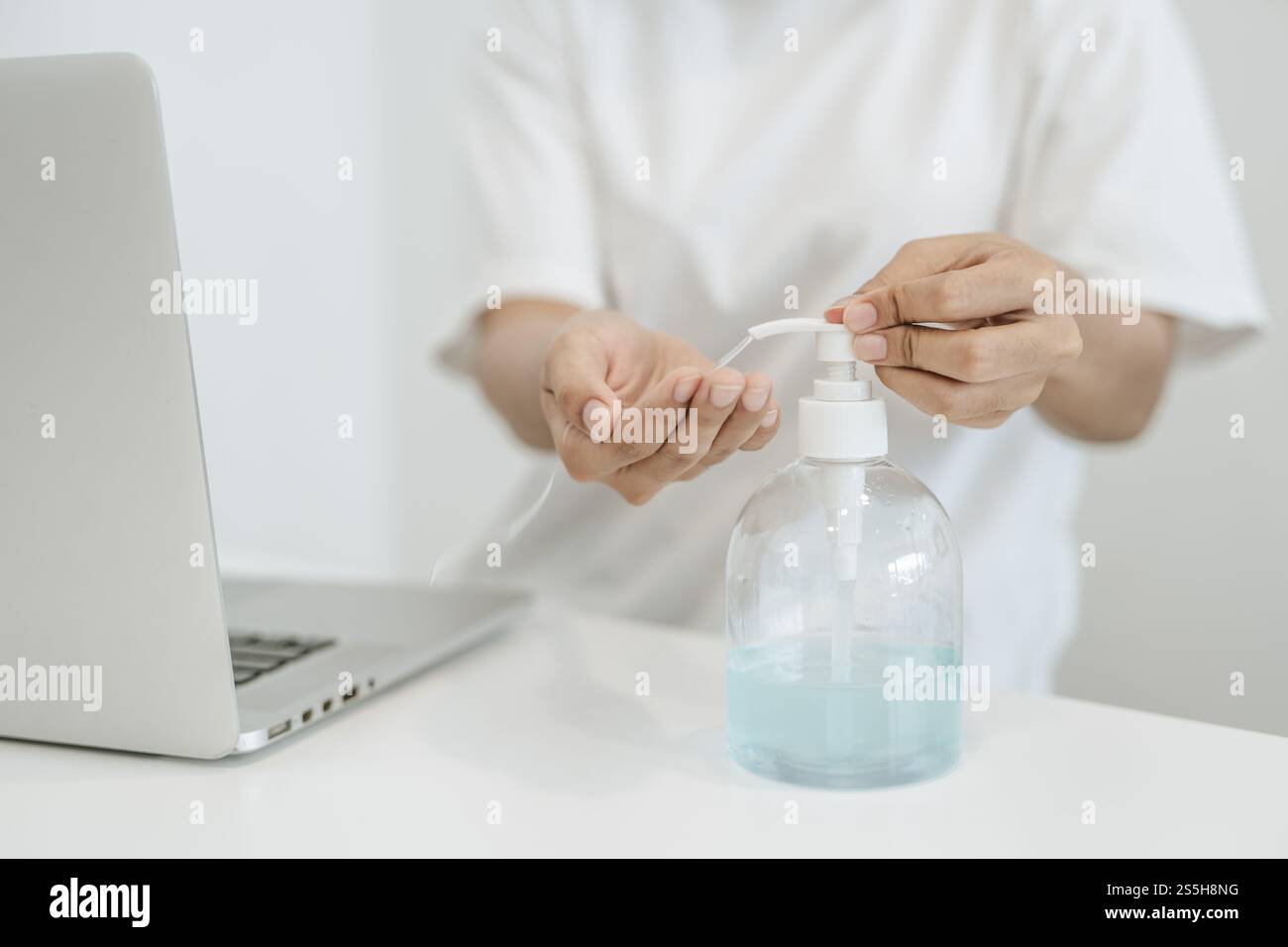 Donne che indossano camicie bianche che premono il gel per lavarsi le mani e pulire le mani. Foto Stock