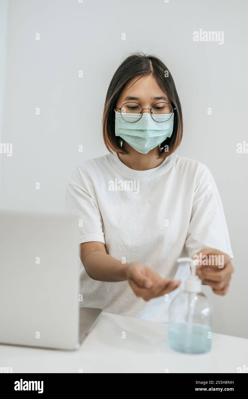 Donne che indossano camicie bianche che premono il gel per lavarsi le mani e pulire le mani. Foto Stock