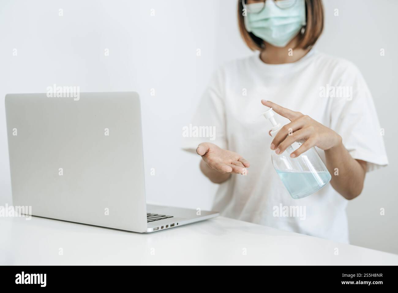 Donne che indossano camicie bianche che premono il gel per lavarsi le mani e pulire le mani. Foto Stock