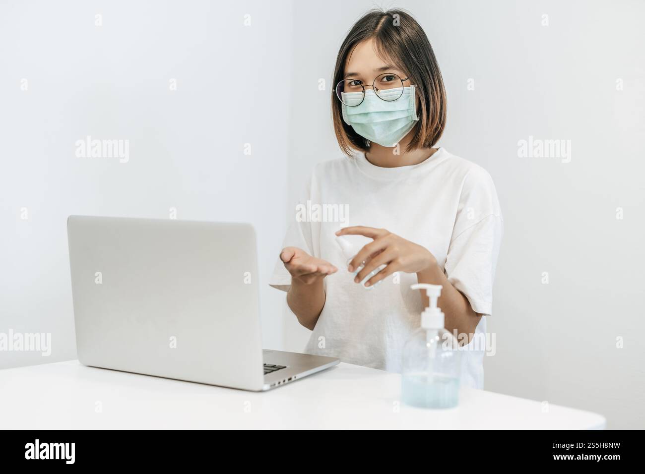 Donne che indossano camicie bianche che premono il gel per lavarsi le mani e pulire le mani. Foto Stock