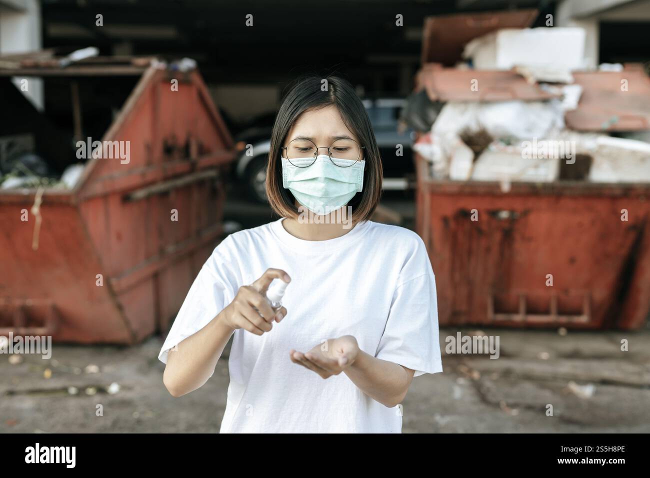 Donne che indossano camicie bianche che premono il gel per lavarsi le mani e pulire le mani. Foto Stock