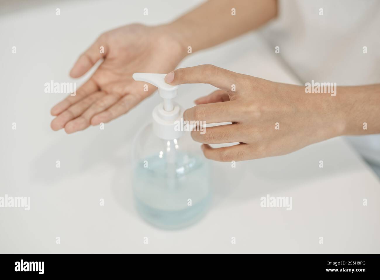 Donne che indossano camicie bianche che premono il gel per lavarsi le mani e pulire le mani. Foto Stock