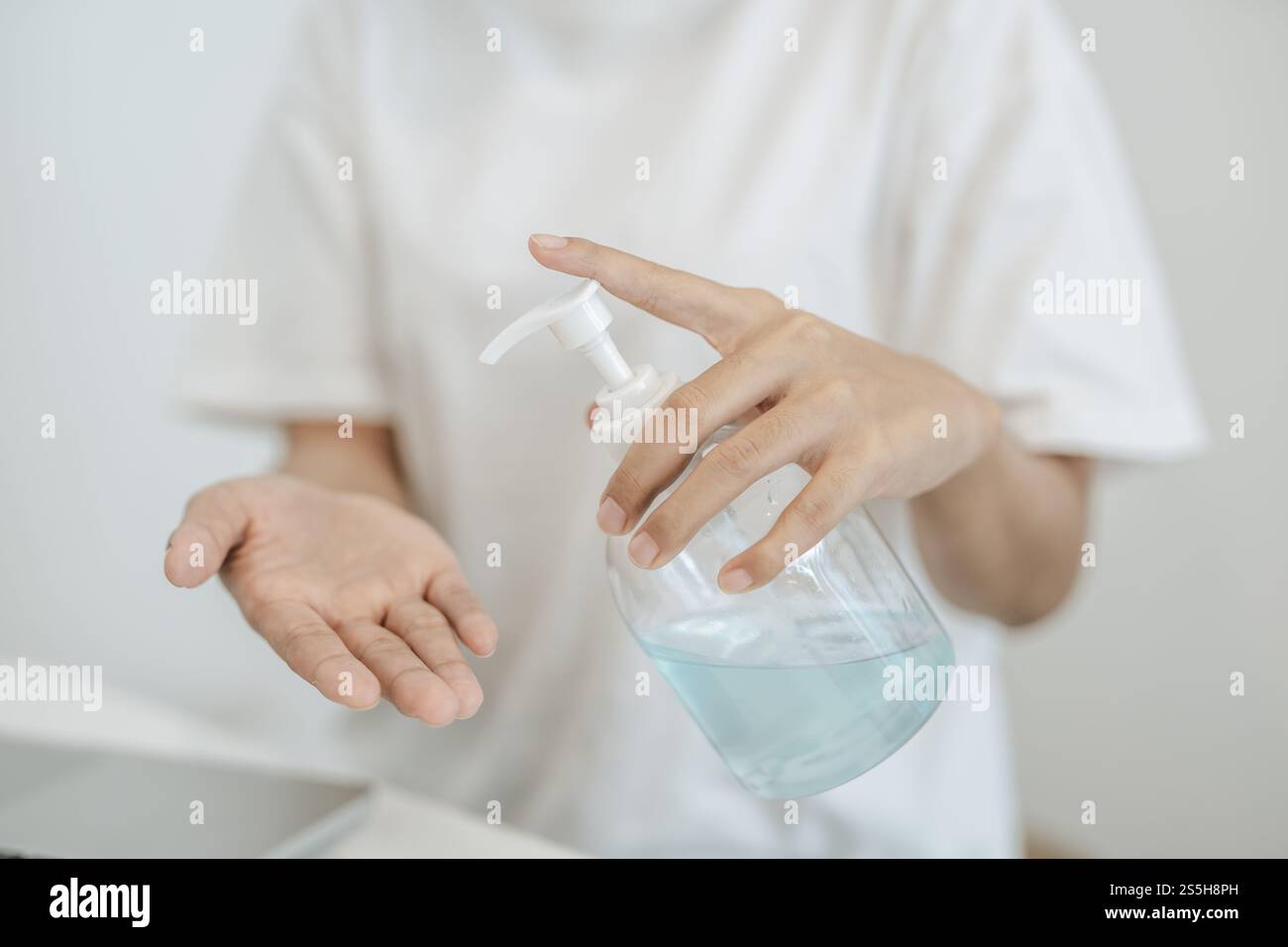 Donne che indossano camicie bianche che premono il gel per lavarsi le mani e pulire le mani. Foto Stock