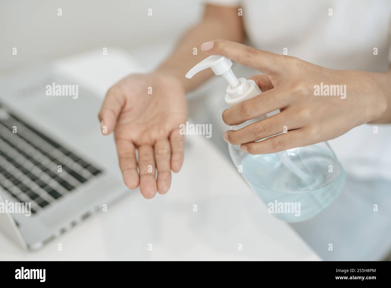 Donne che indossano camicie bianche che premono il gel per lavarsi le mani e pulire le mani. Foto Stock