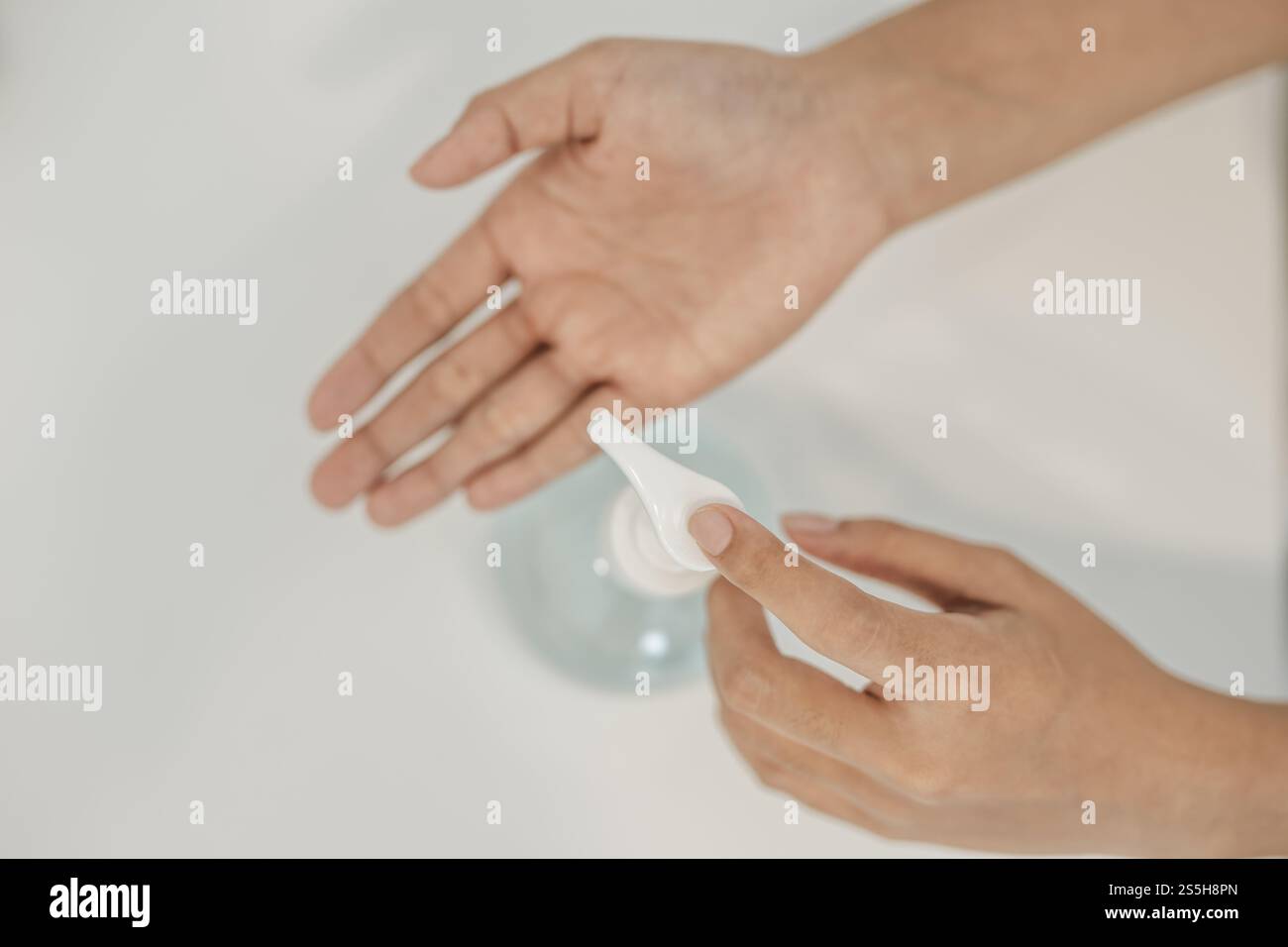 Donne che indossano camicie bianche che premono il gel per lavarsi le mani e pulire le mani. Foto Stock