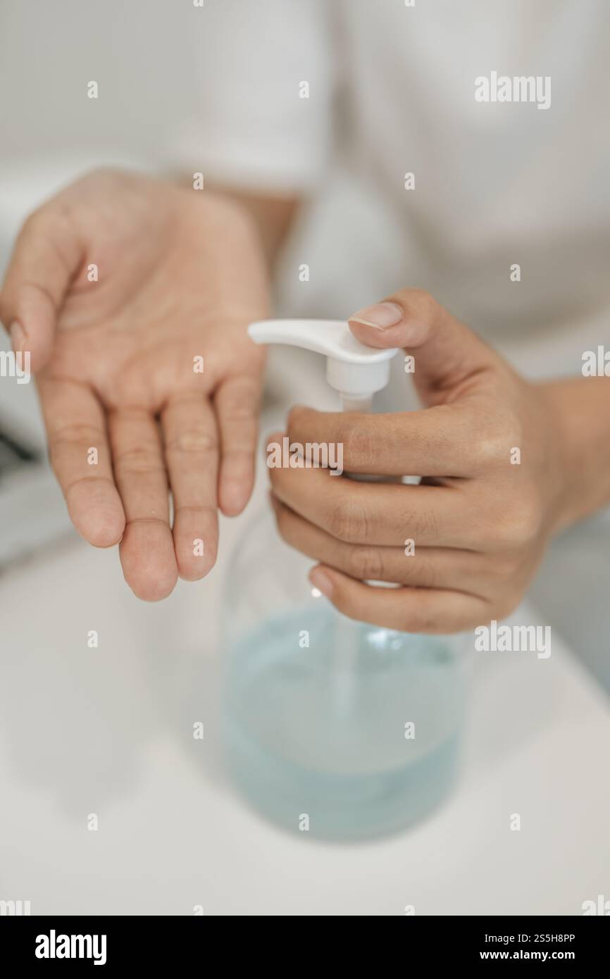 Donne che indossano camicie bianche che premono il gel per lavarsi le mani e pulire le mani. Foto Stock