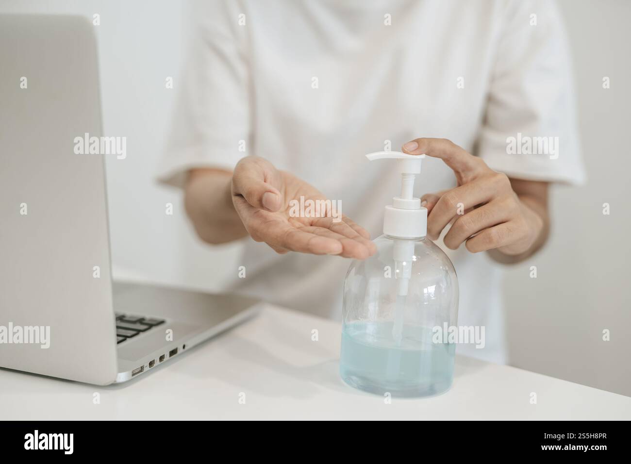 Donne che indossano camicie bianche che premono il gel per lavarsi le mani e pulire le mani. Foto Stock