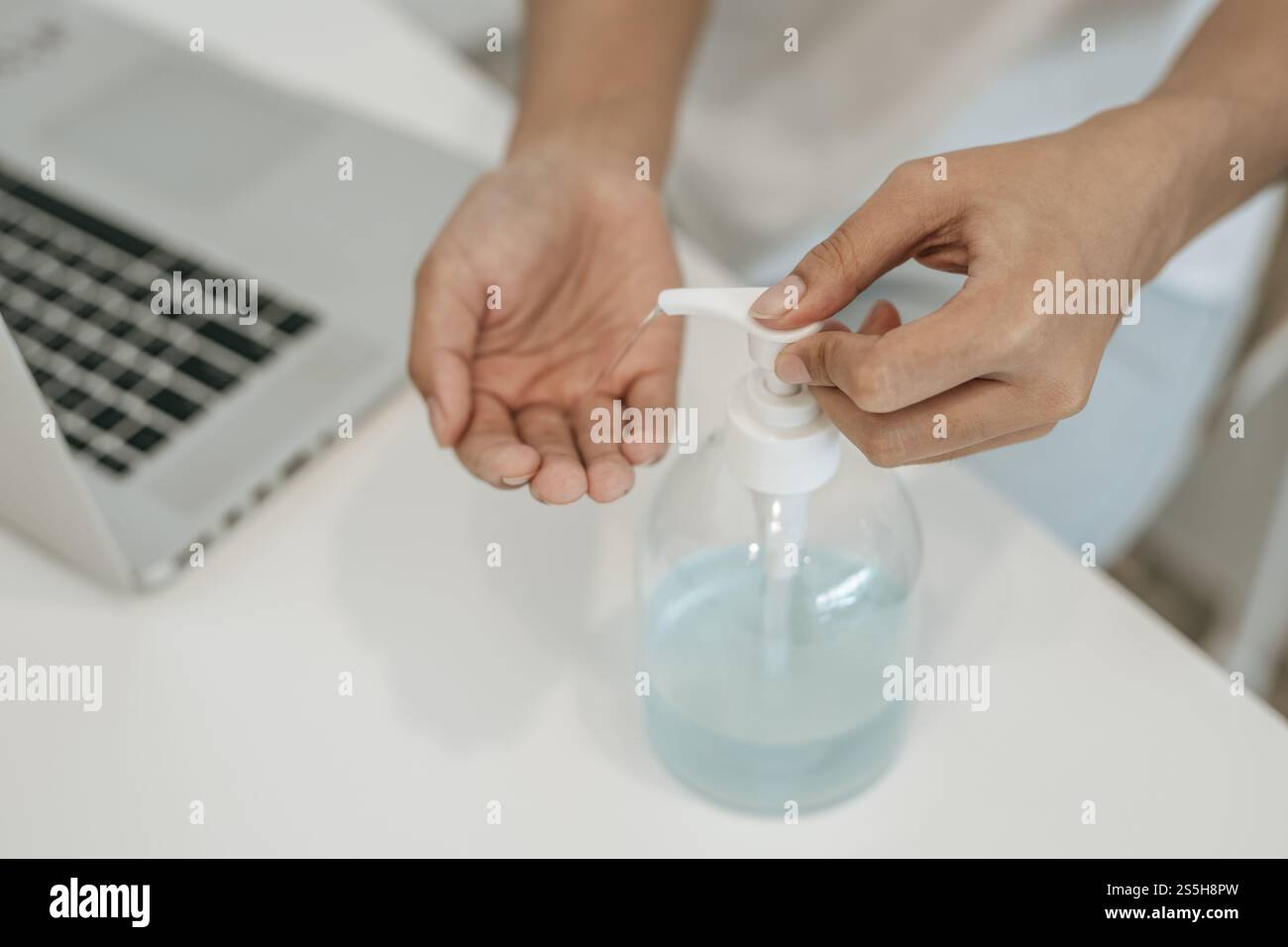 Donne che indossano camicie bianche che premono il gel per lavarsi le mani e pulire le mani. Foto Stock