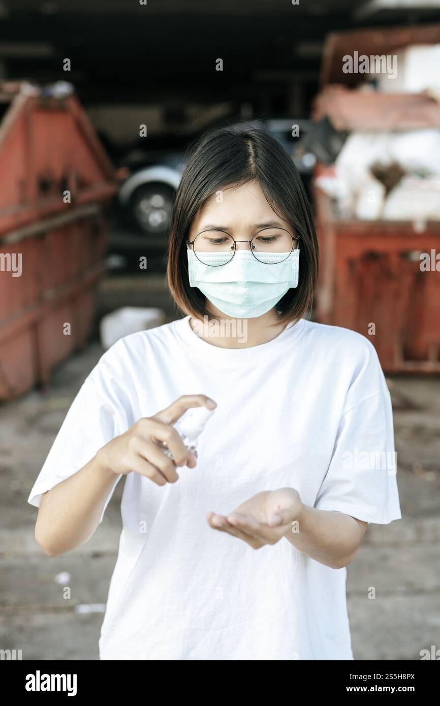 Donne che indossano camicie bianche che premono il gel per lavarsi le mani e pulire le mani. Foto Stock