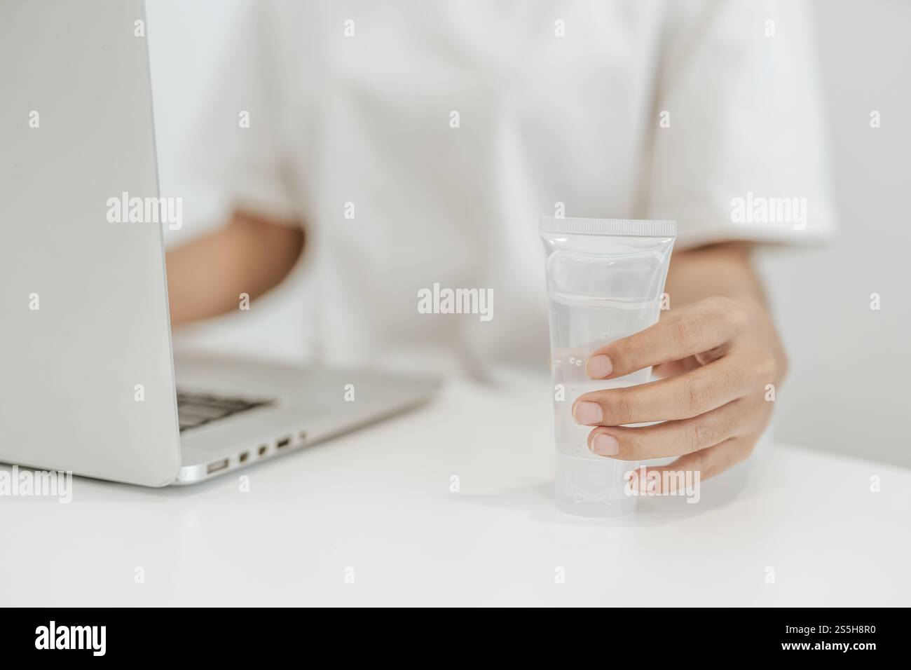 Donne che indossano camicie bianche che premono il gel per lavarsi le mani e pulire le mani. Foto Stock