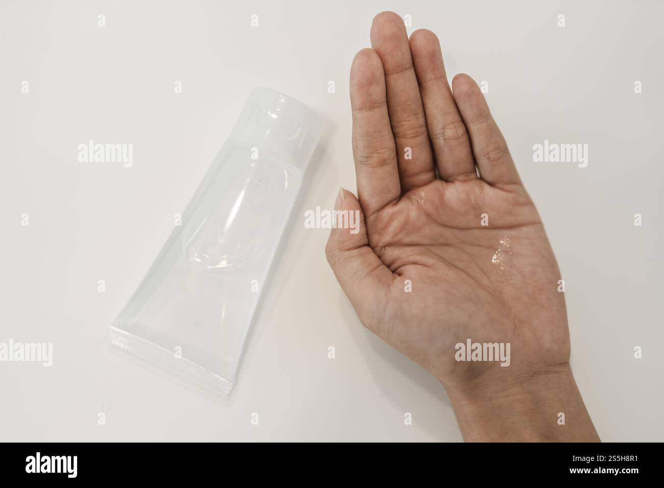 Donne che indossano camicie bianche che premono il gel per lavarsi le mani e pulire le mani. Foto Stock