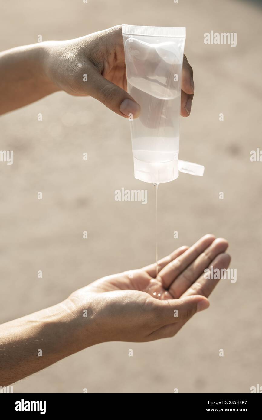 Donne che indossano camicie bianche che premono il gel per lavarsi le mani e pulire le mani. Foto Stock