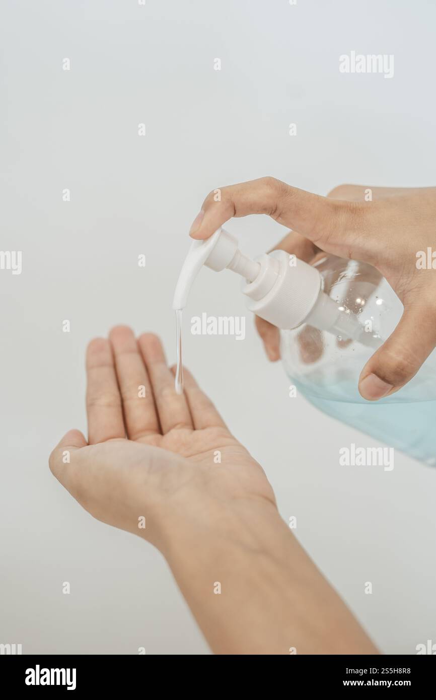 Donne che indossano camicie bianche che premono il gel per lavarsi le mani e pulire le mani. Foto Stock