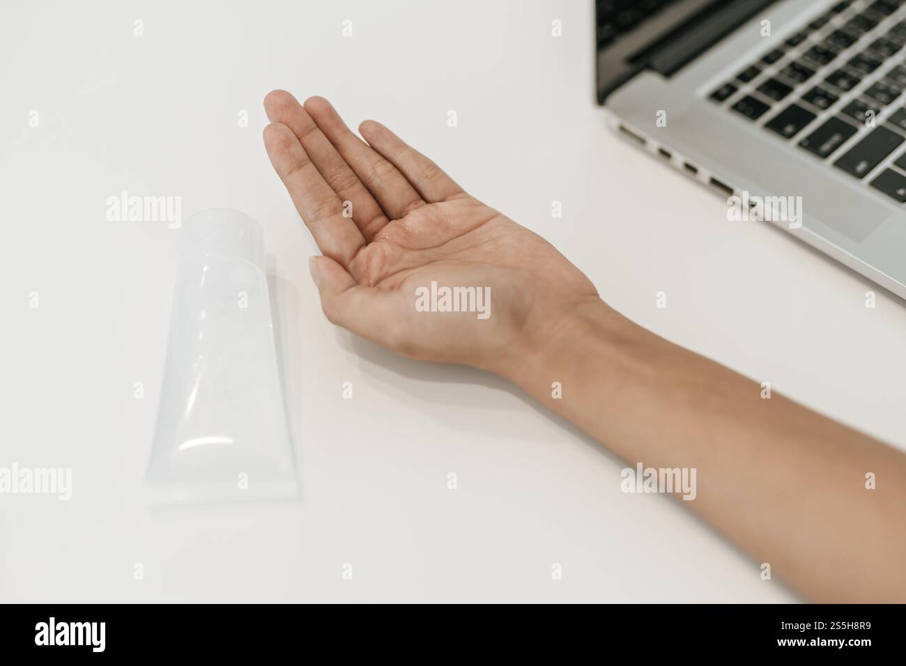 Donne che indossano camicie bianche che premono il gel per lavarsi le mani e pulire le mani. Foto Stock