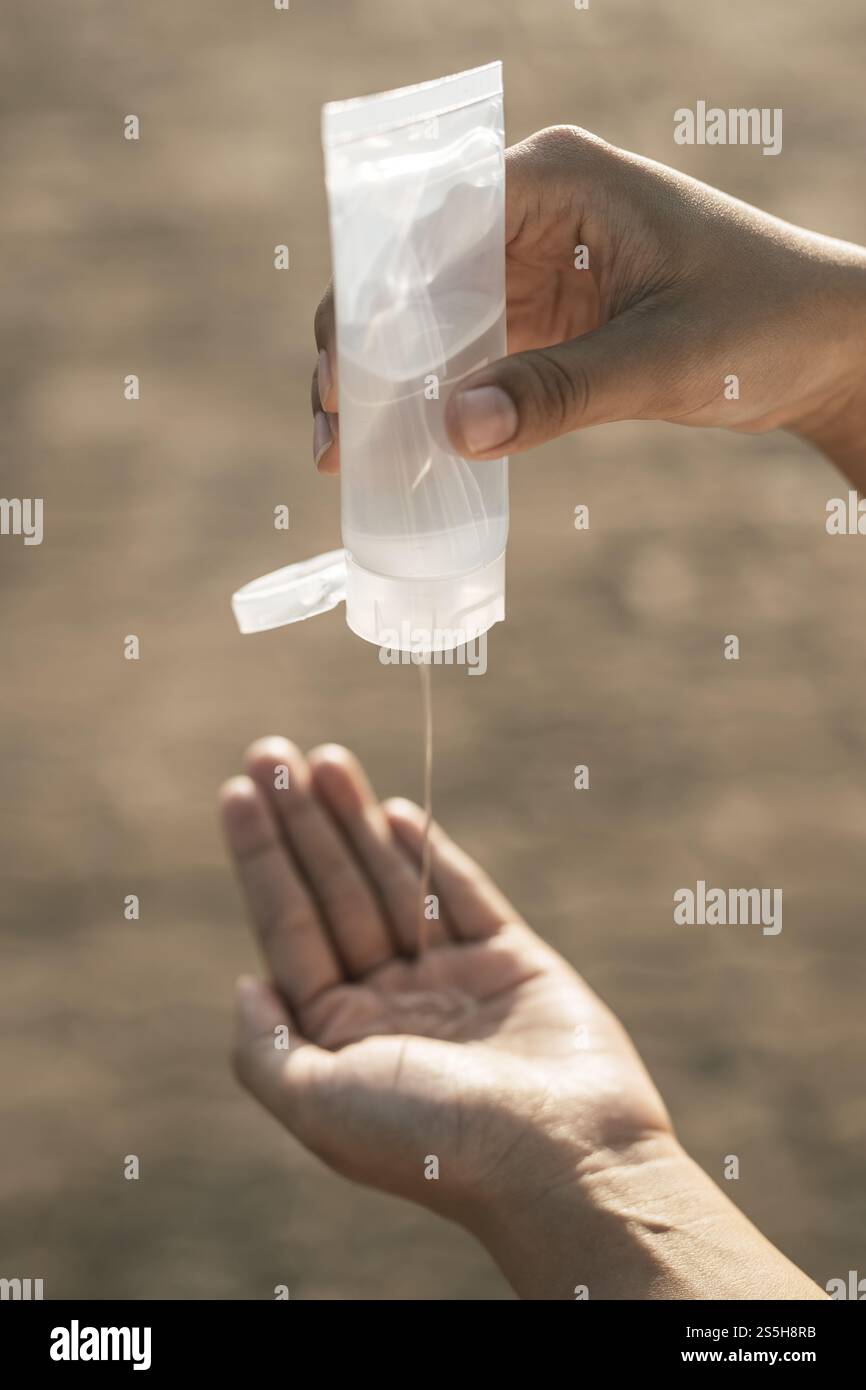 Donne che indossano camicie bianche che premono il gel per lavarsi le mani e pulire le mani. Foto Stock
