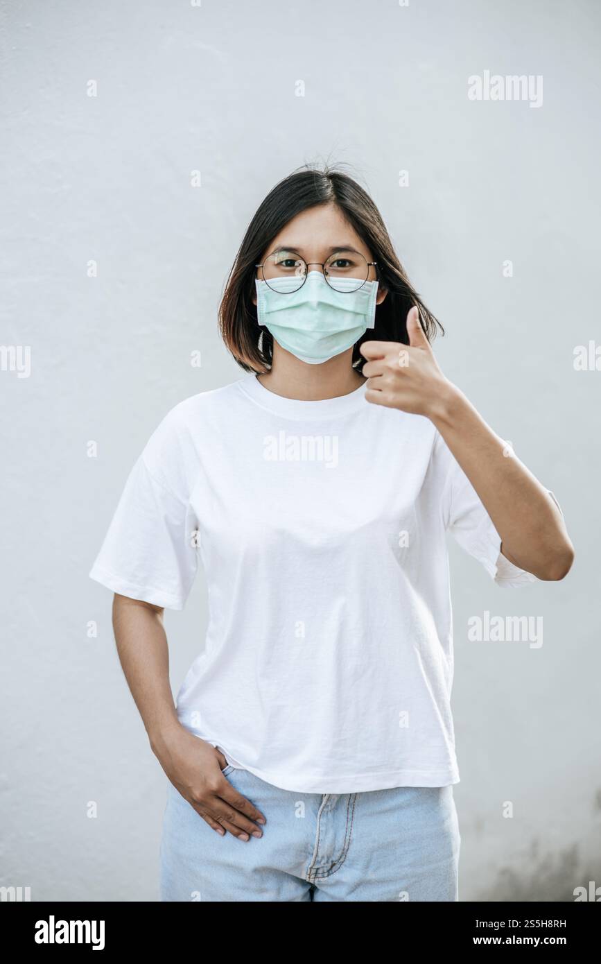 Le donne indossano le maschere e le segnano con i pollici in alto. Foto Stock