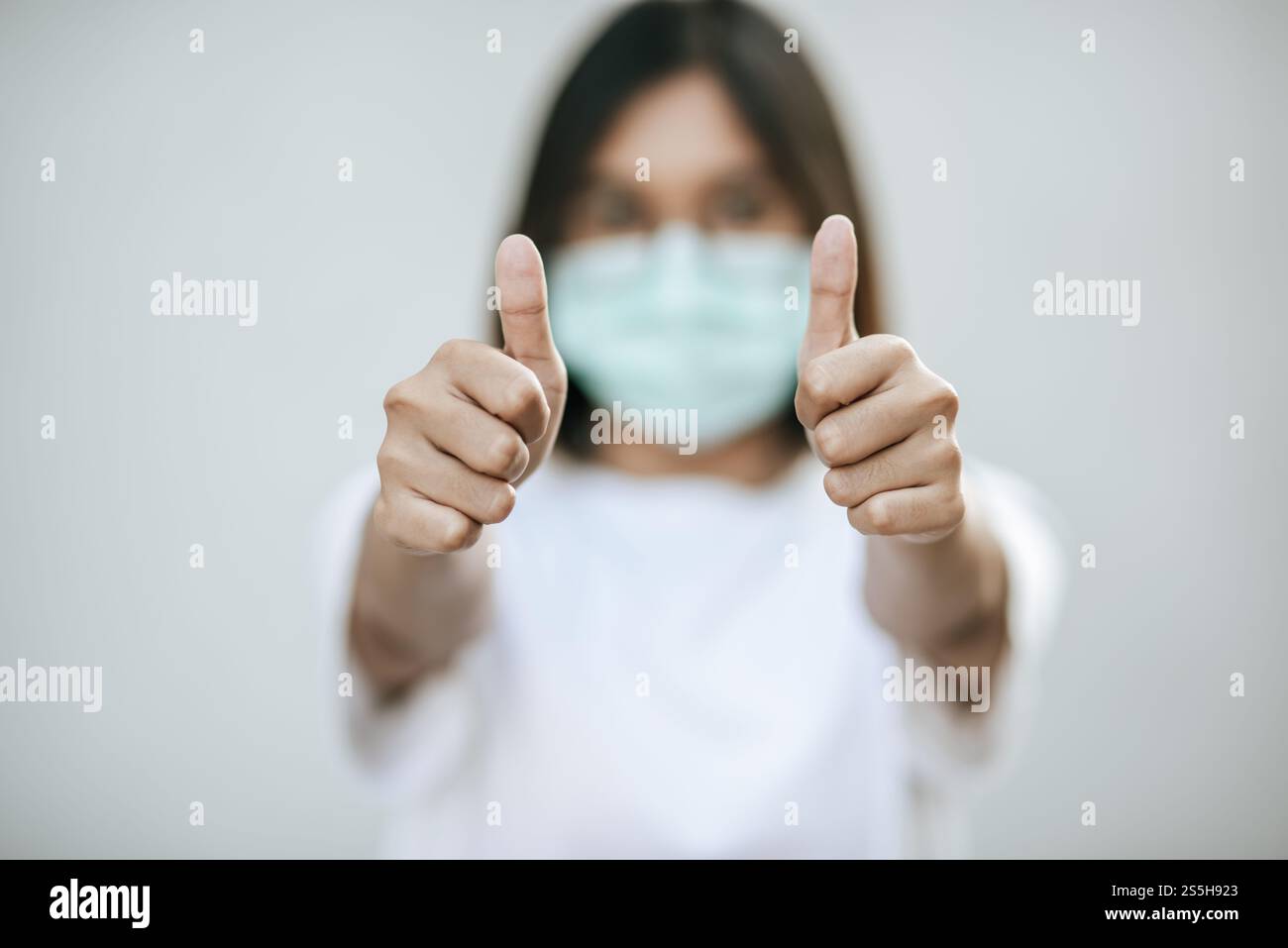 Le donne indossano le maschere e le segnano con i pollici in alto. Foto Stock