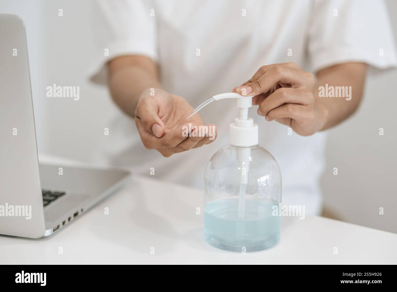 Donne che indossano camicie bianche che premono il gel per lavarsi le mani e pulire le mani. Foto Stock