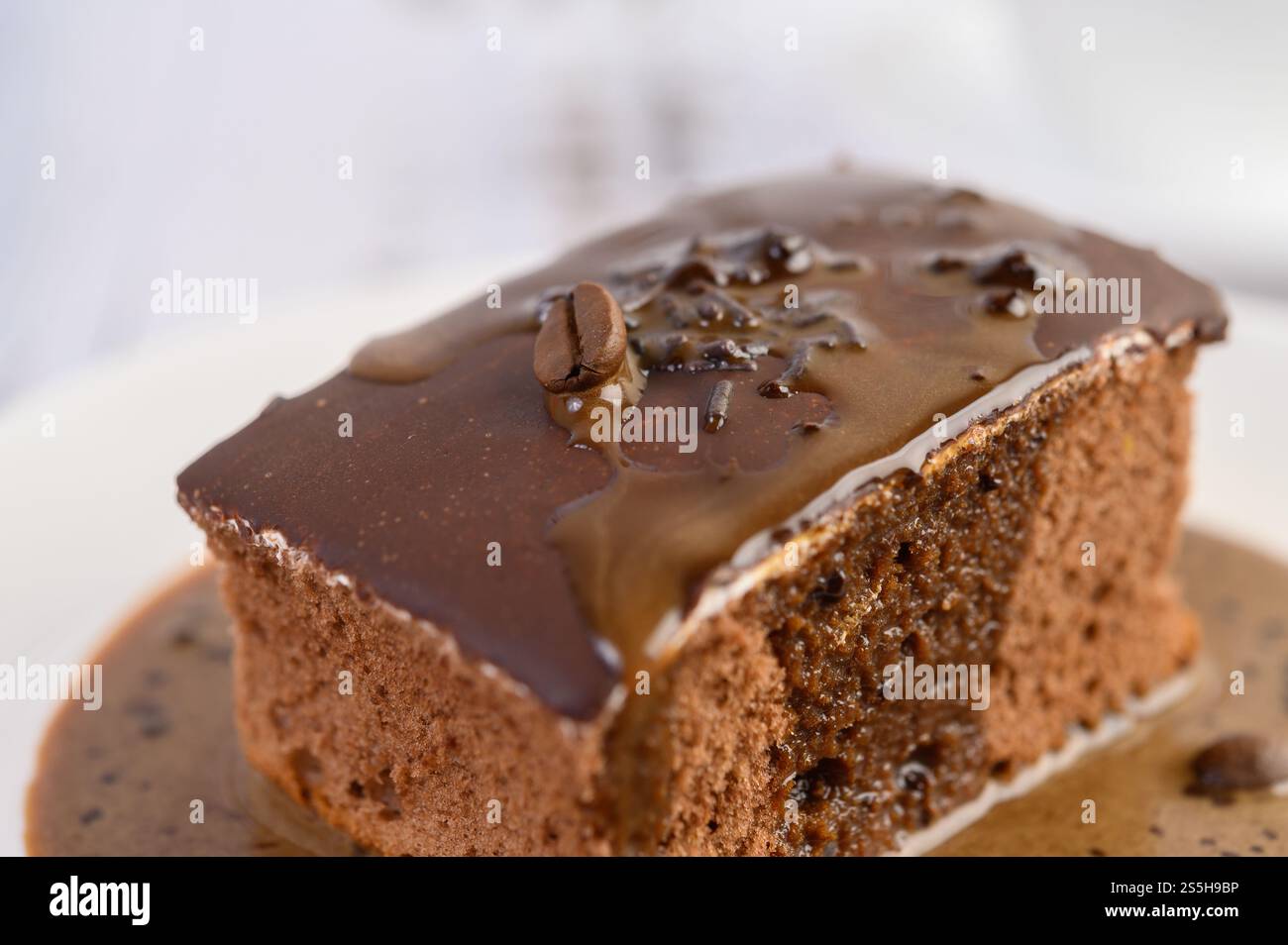 Torta al cioccolato ricoperta di caffè su un piatto bianco con chicchi di caffè su un tavolo di legno. Foto Stock