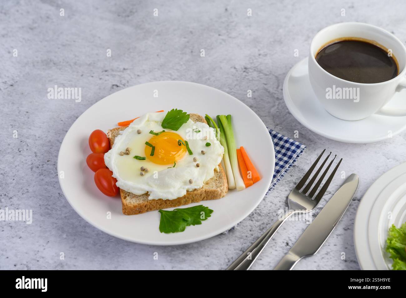 Un uovo fritto adagiato su un toast, ricoperto di semi di pepe con carote e cipollotti. Foto Stock
