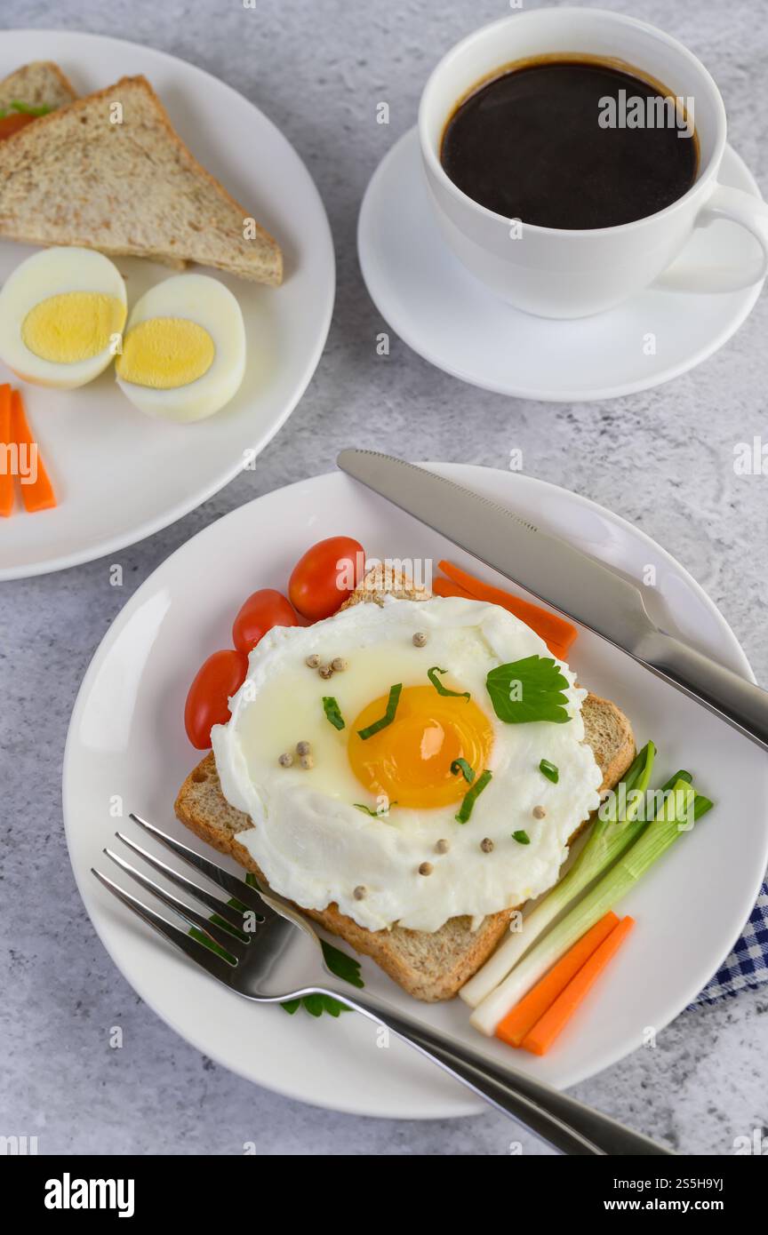 Un uovo fritto adagiato su un toast, ricoperto di semi di pepe con carote e cipollotti. Foto Stock