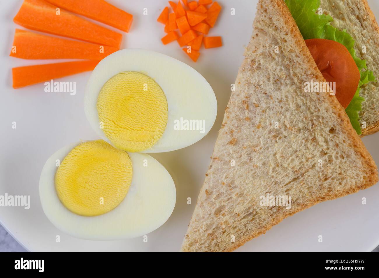 Un uovo fritto adagiato su un toast, ricoperto di semi di pepe con carote e cipollotti. Foto Stock