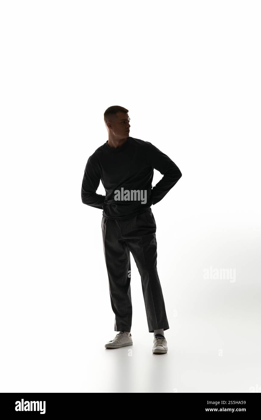 Un giovane uomo si trova in una posizione elegante su uno sfondo luminoso e minimalista. Foto Stock Un giovane uomo si trova in una posizione elegante su uno sfondo luminoso e minimalista. Foto Stock