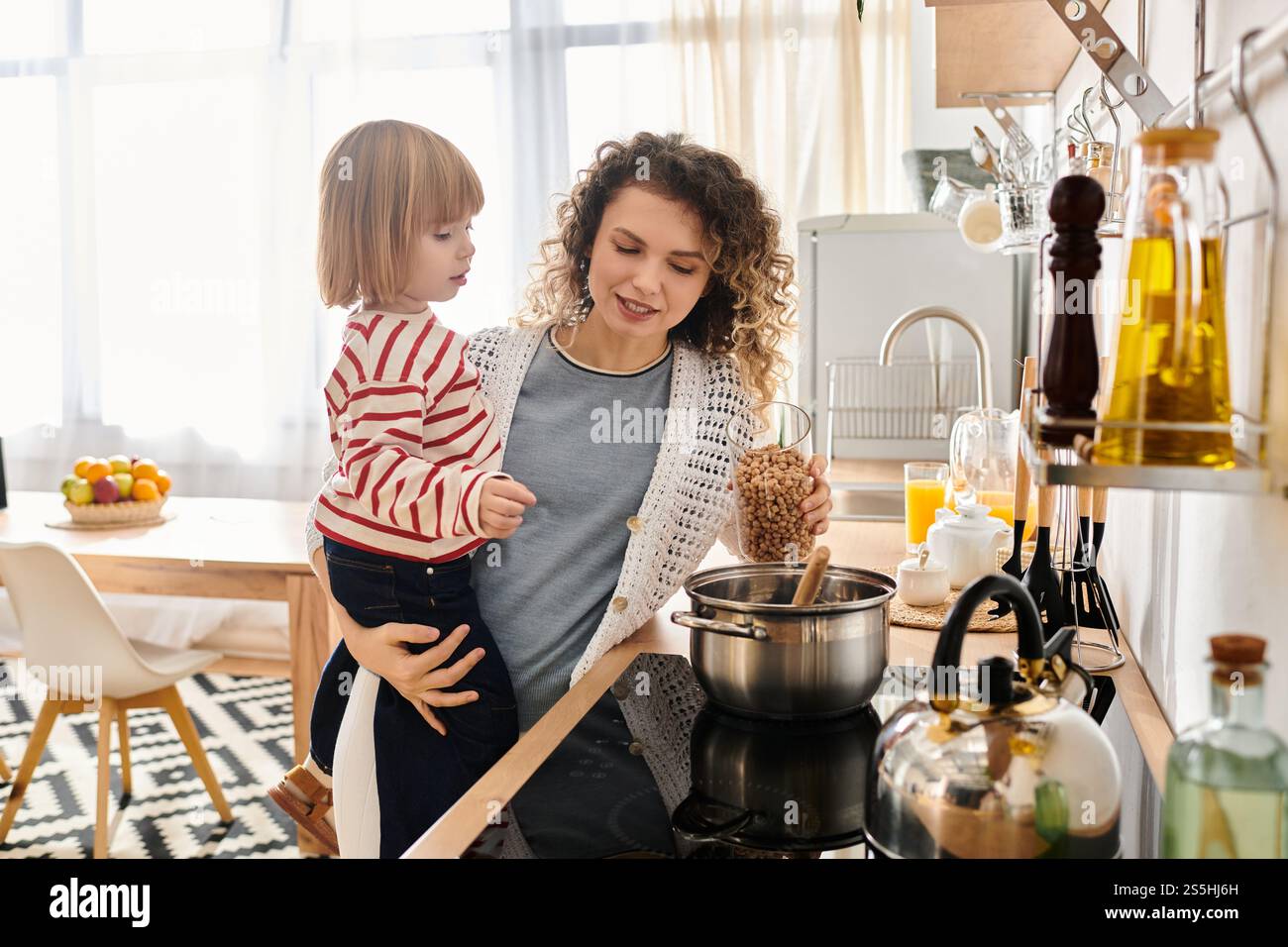 Madre e figlia condividono un momento di gioia mentre preparano un pasto a casa, abbracciando la vita familiare. Foto Stock