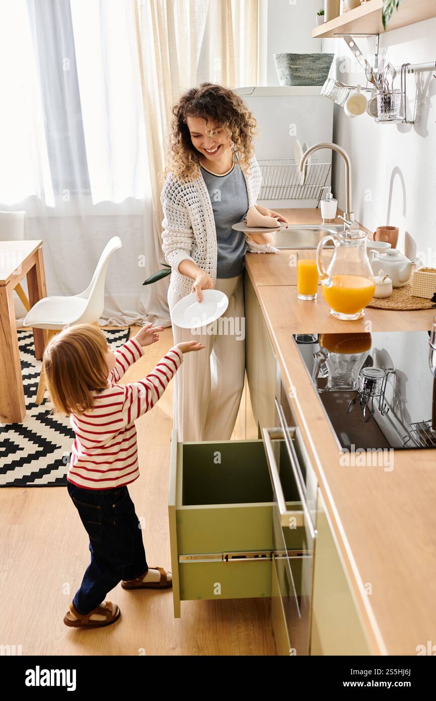 Una madre gioiosa e sua figlia condividono un momento di gioco nell'accogliente cucina per preparare un pasto. Foto Stock