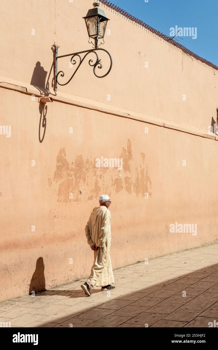 Uomo che cammina nella Medina di Marrakech del Marocco con una lampada sopra la testa Foto Stock