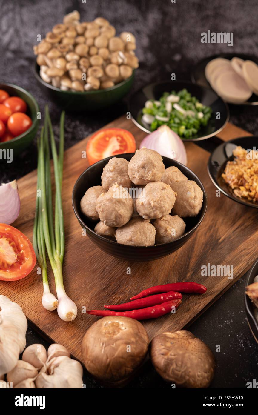 Polpette di maiale in tazze nere con cipolla primaverile, peperoncino, funghi shiitake e pomodoro. Foto Stock