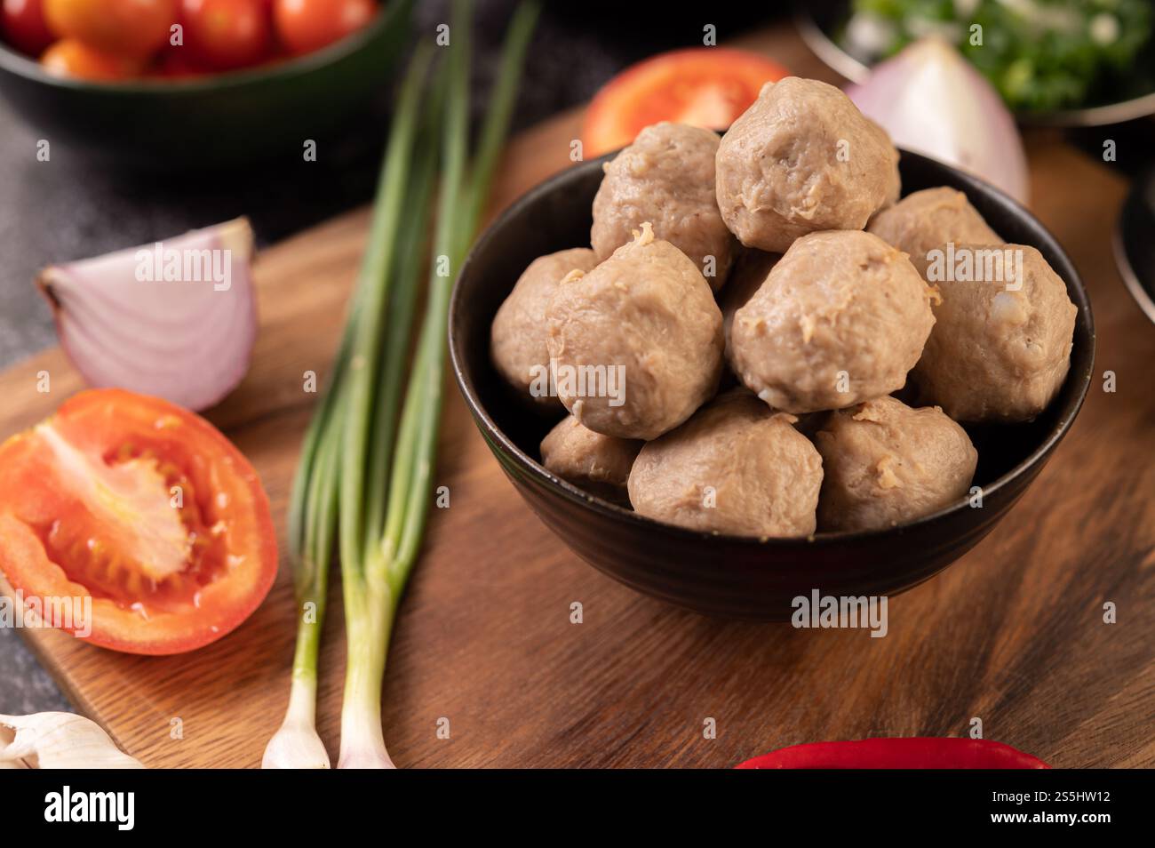 Polpette di maiale in tazze nere con cipolla primaverile, peperoncino, funghi shiitake e pomodoro. Foto Stock