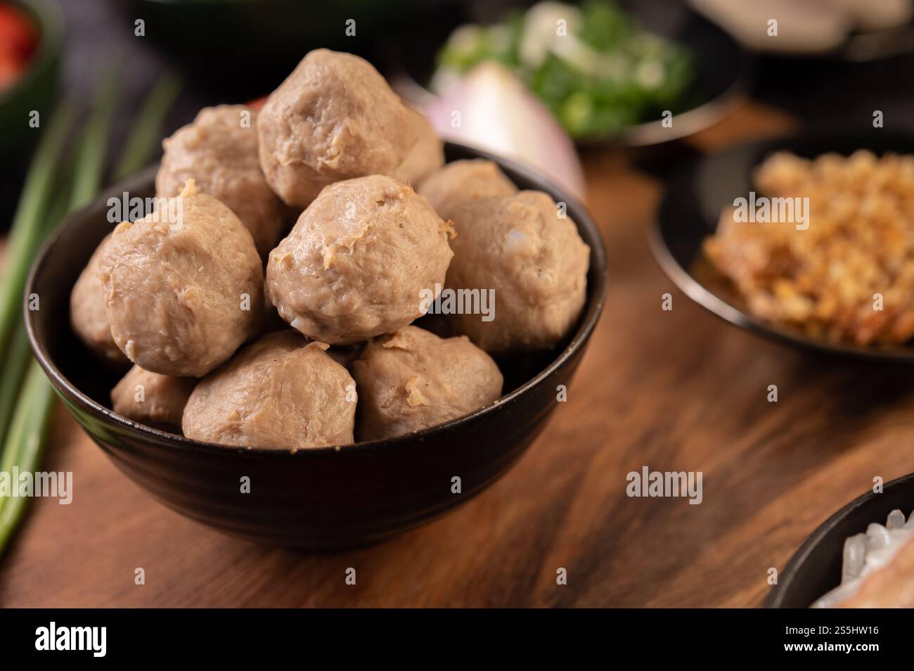 Le palline di maiale in tazze nere sono posizionate su un tavolo di legno. Foto Stock