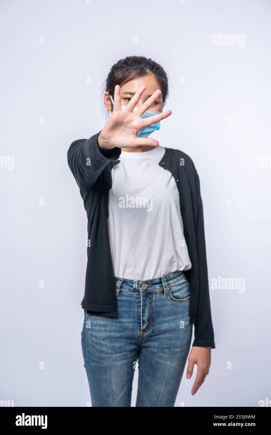 Una donna è malata in piedi con indosso una maschera e un segno proibito a mano Foto Stock