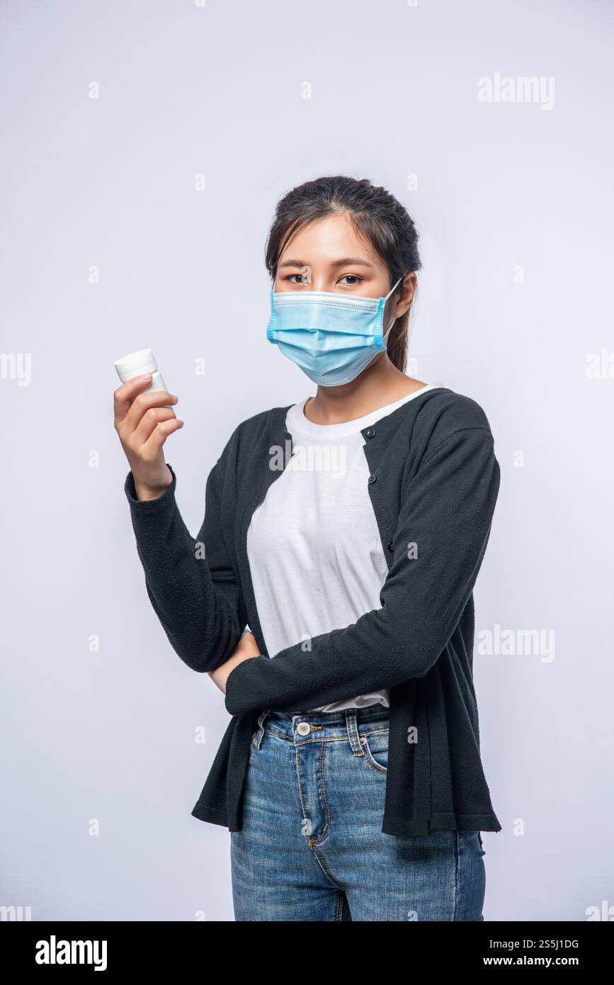 Una donna malata in piedi con una bottiglia di medicina Foto Stock