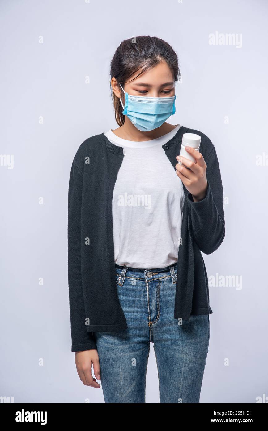 Una donna malata in piedi con una bottiglia di medicina Foto Stock