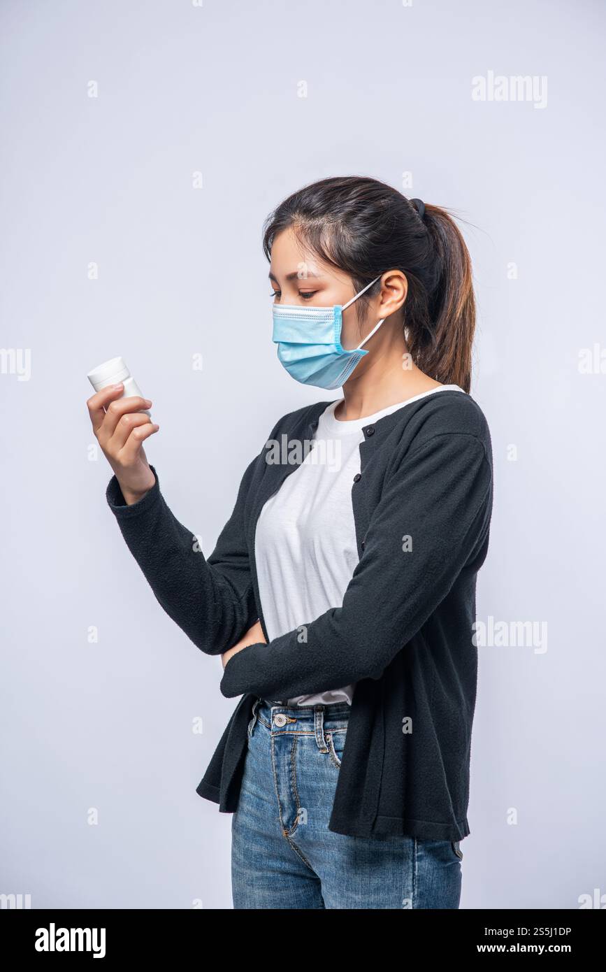 Una donna malata in piedi con una bottiglia di medicina Foto Stock
