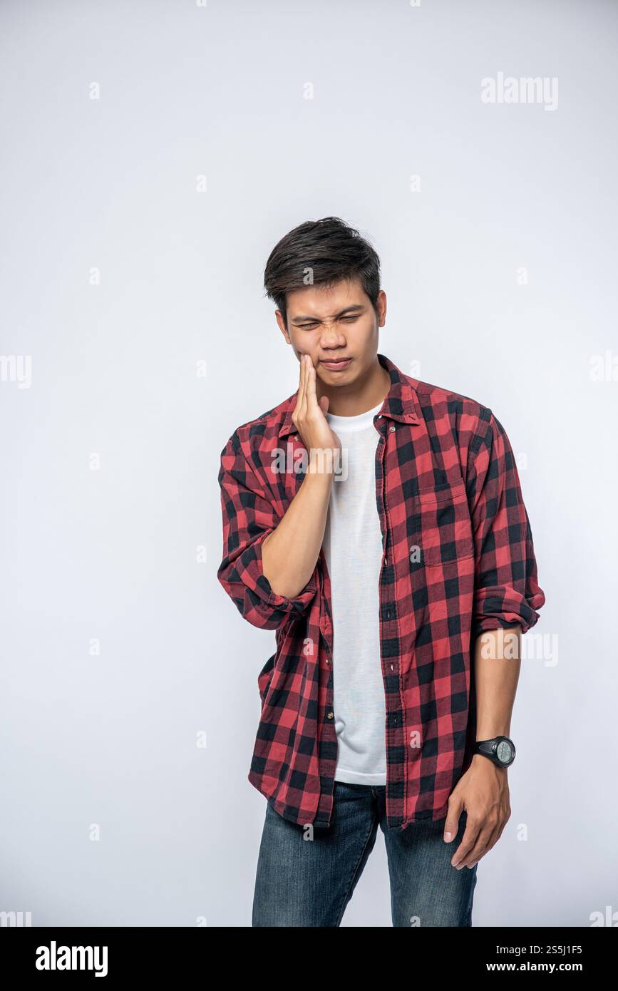 Un uomo malato di mal di denti e una mano che tiene la guancia Foto Stock