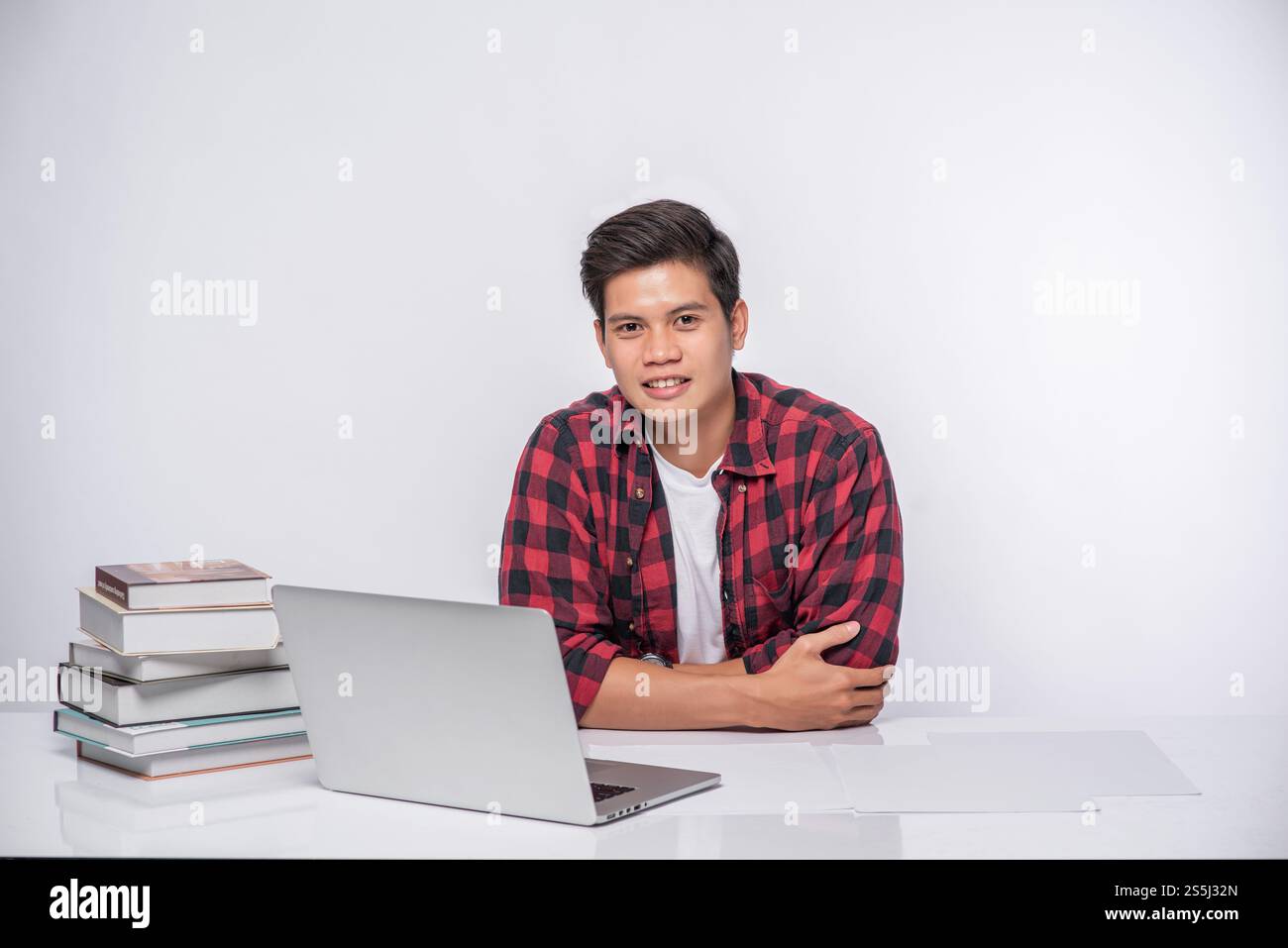 Un uomo che indossa una camicia a righe usa un notebook per lavorare. Foto Stock