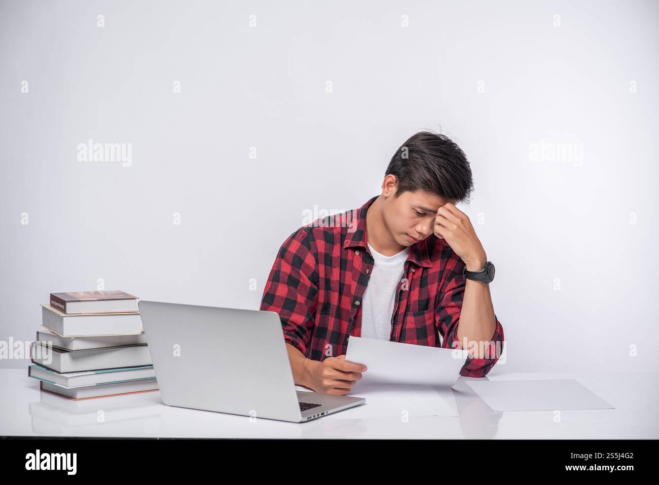 Un uomo che usa un portatile in ufficio e fa un'analisi documentale. Foto Stock