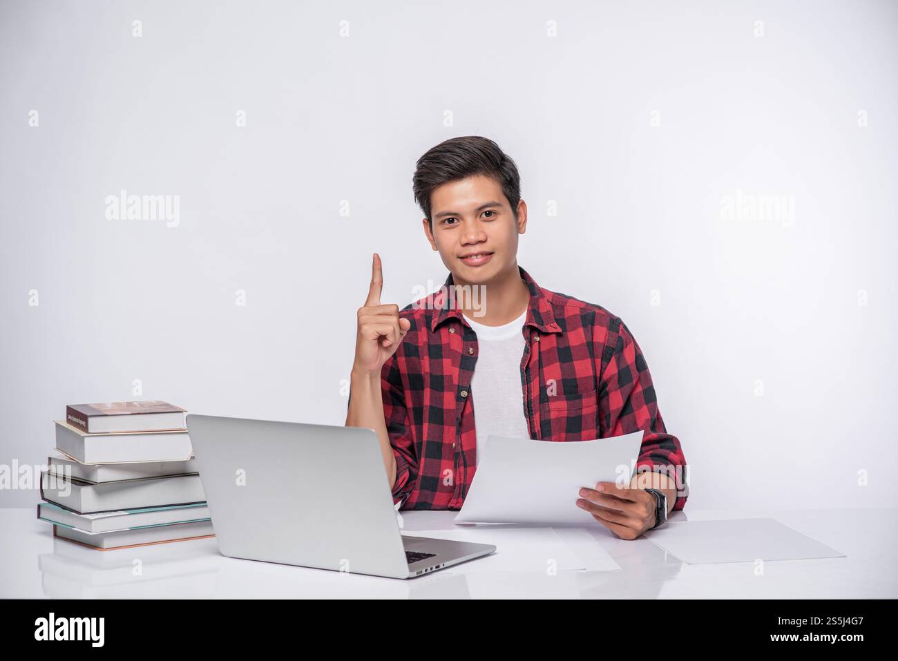 Un uomo che usa un portatile in ufficio e fa un'analisi documentale. Foto Stock